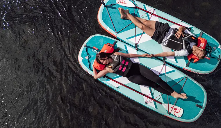 two people laying on paddleboards in the water