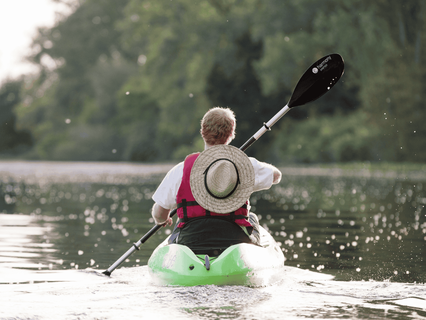 man kayaking in wades bayou with a straw hat