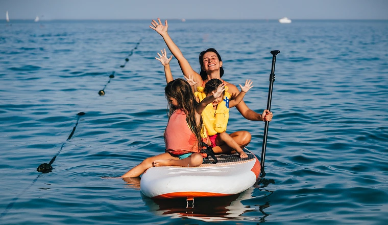 women on a paddleboard with two kids