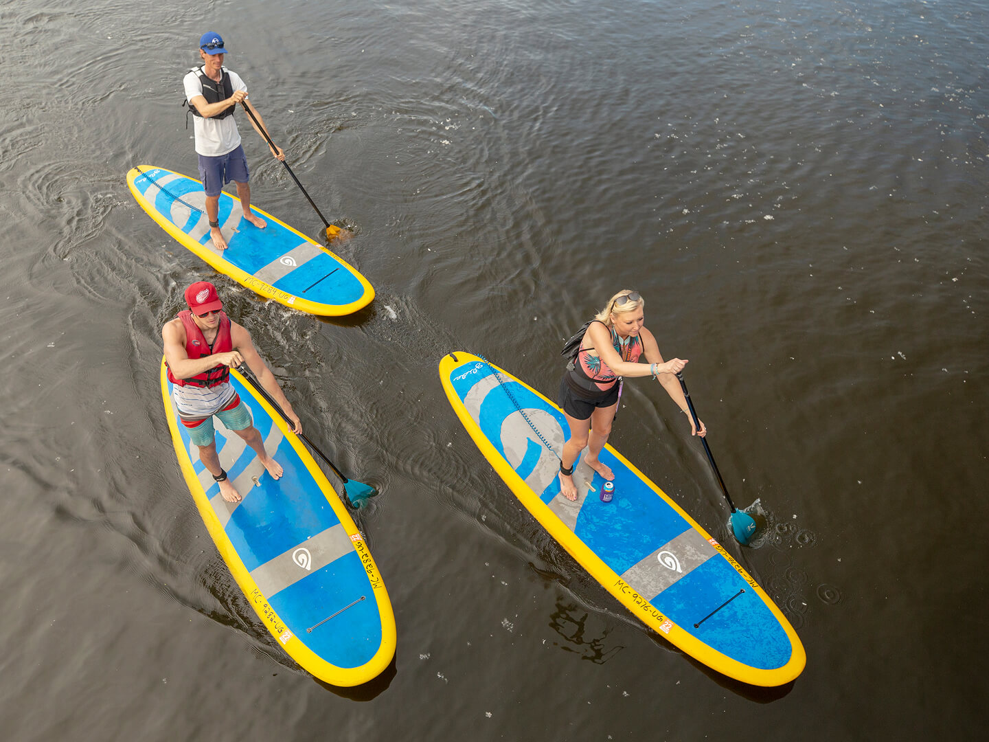 three people paddleboarding on the river