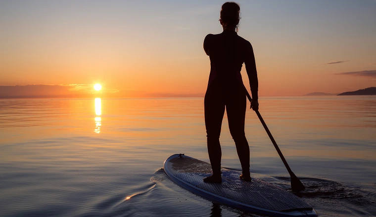people paddleboarding at sunset